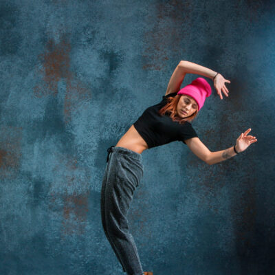 Young girl break dancing on blue studio background.